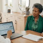 Une conseillère financière présente des stratégies pour réduire son IFI (Impôt sur la Fortune Immobilière) à un couple de retraités attentif, en leur montrant des tableaux et graphiques sur son ordinateur portable lors d'un rendez-vous.