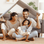 famille parents avec leur enfant, assis dans le salon portant le toit d'une petite maison au dessus de leurs têtes, symbolisant l'assurance